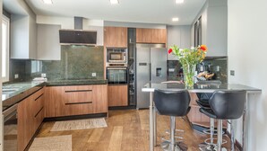 Eine moderne Küche mit Holzschränken, Edelstahlgeräten und einer Bar mit Hockern.