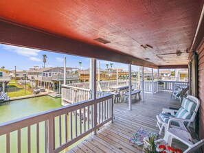 Relax on the deck overlooking the marina, surrounded by potted plants and comfortable seating.