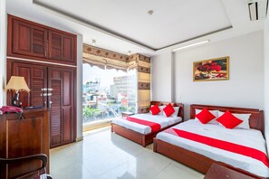 Une chambre d’hôtel avec deux lits, un bureau et une grande fenêtre donnant sur la ville.