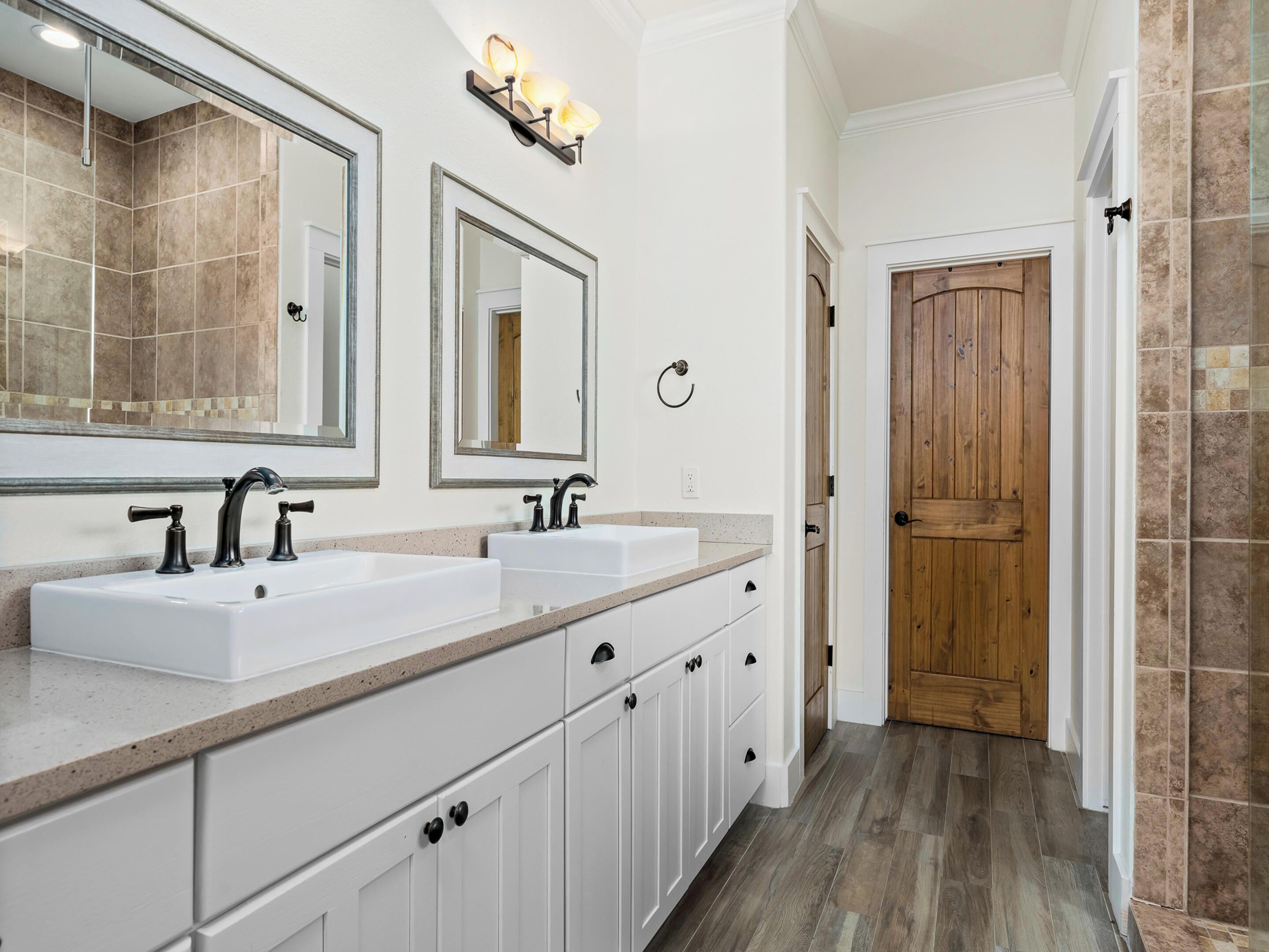 A bathroom with two sinks, a mirror, and a wooden door.