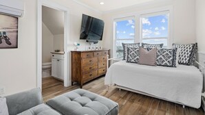 Ein Schlafzimmer mit Bett, Fernseher, Kommode und einem Fenster mit Blick.