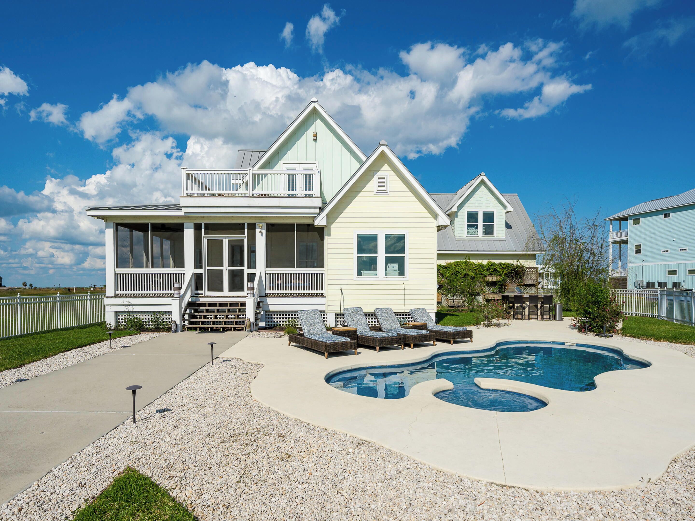 A two-story house with a large backyard, a swimming pool, and a covered patio area.