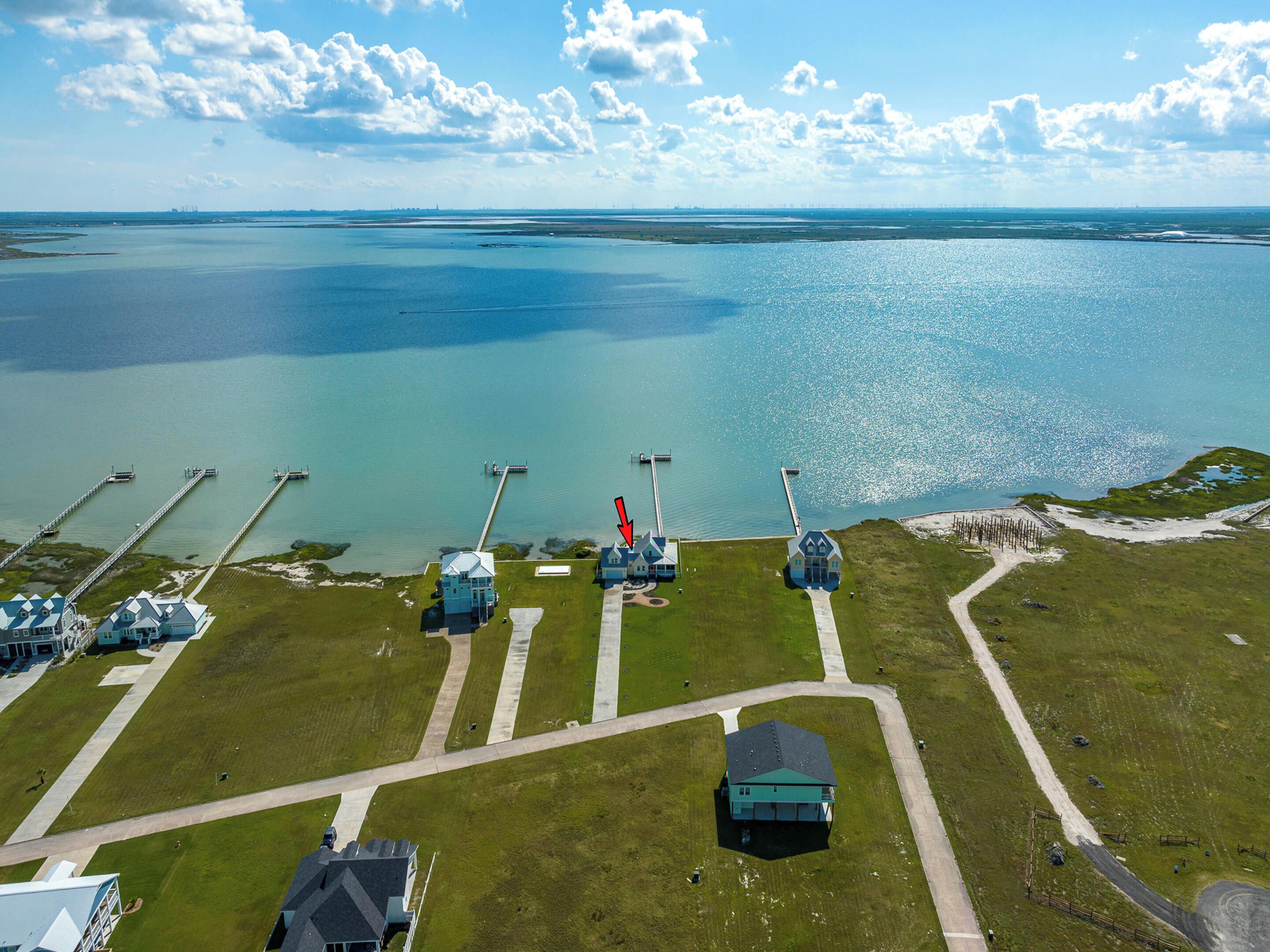 An aerial view of a coastal property with multiple buildings, a dock, and a large body of water.