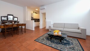 Una sala de estar con sofá, mesa de centro y comedor con sillas y una mesa.