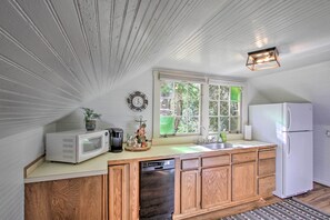 A kitchen with wooden cabinets, a white refrigerator, a microwave, and a dishwasher.