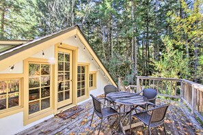 A wooden deck with a table and chairs, surrounded by a forest. - Owls Nest Studio w/ Hot Tub: Hike Nearby! (Ashford)