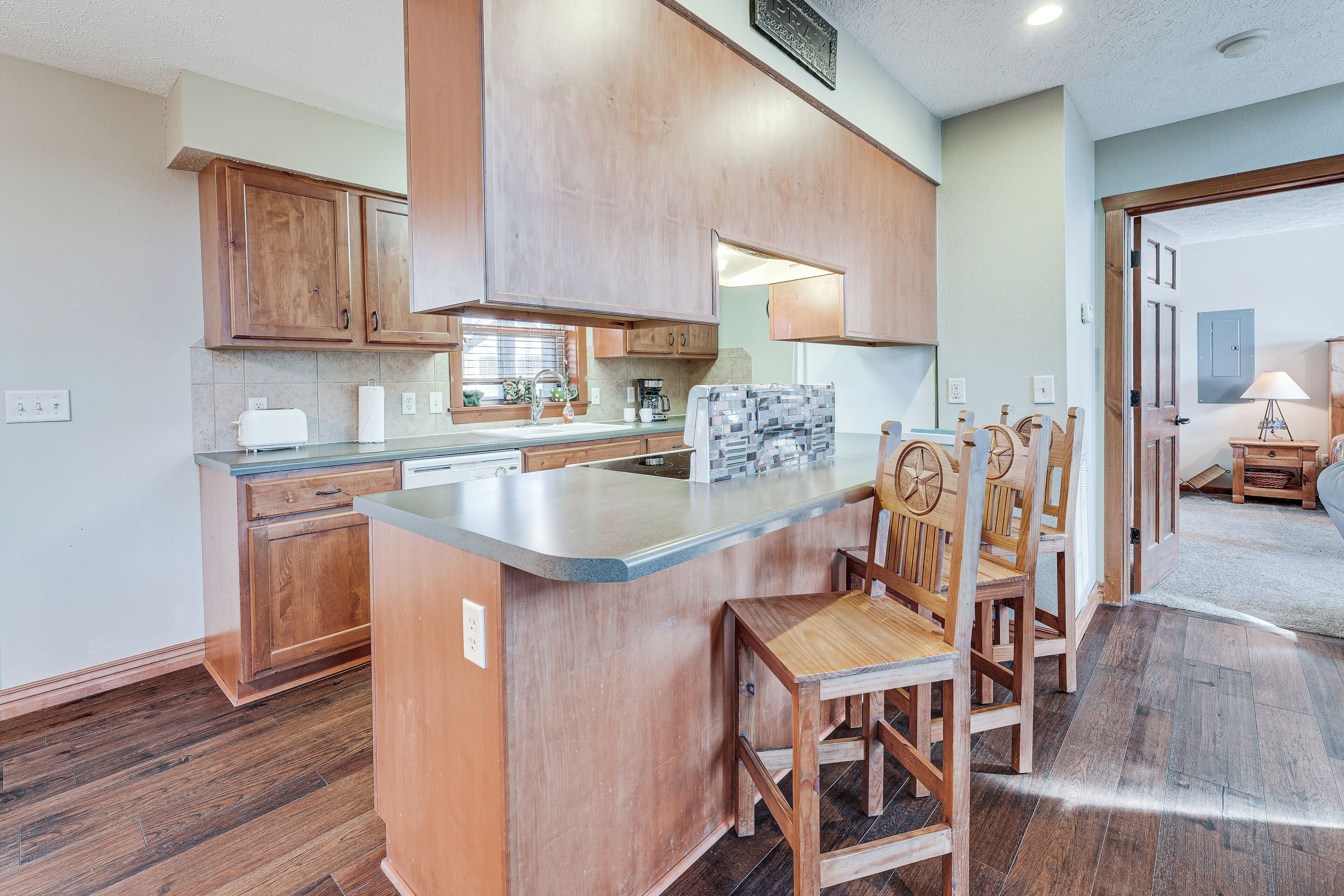 Una cocina con armarios de madera, encimera de mármol y una isla central con sillas.