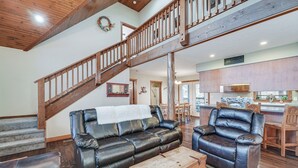 A spacious living room with a leather sofa, a wooden coffee table, and a staircase leading to an upper level. - Families Welcome! Branson Resort-style Getaway (Branson)