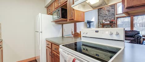 Une cuisine avec des meubles de rangement en bois, un réfrigérateur, un four à micro-ondes, un four et une cuisinière.