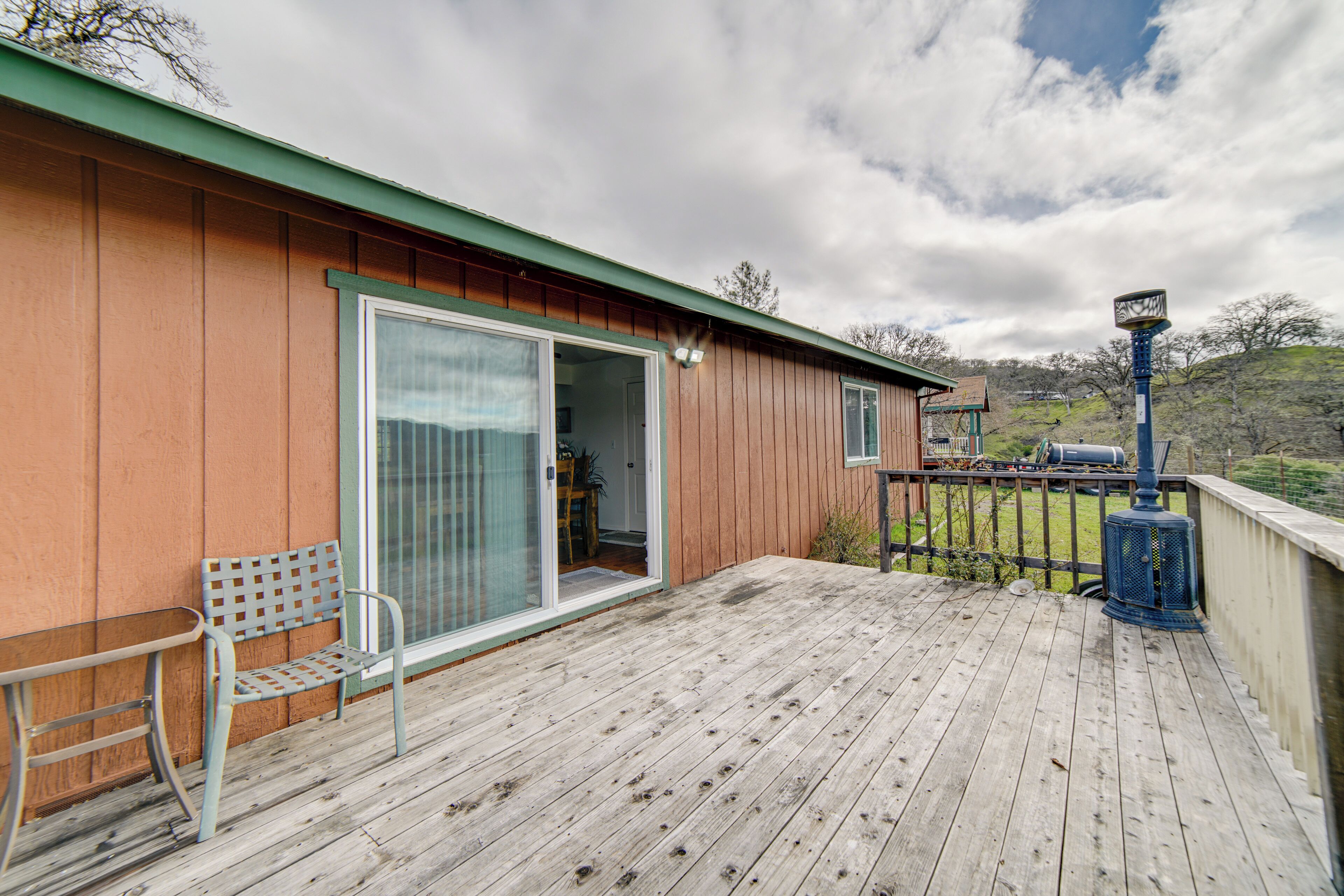 A wooden deck with a bench and a sliding glass door leading to a room.