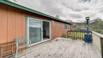 A wooden deck with a bench and a sliding glass door leading to a room.