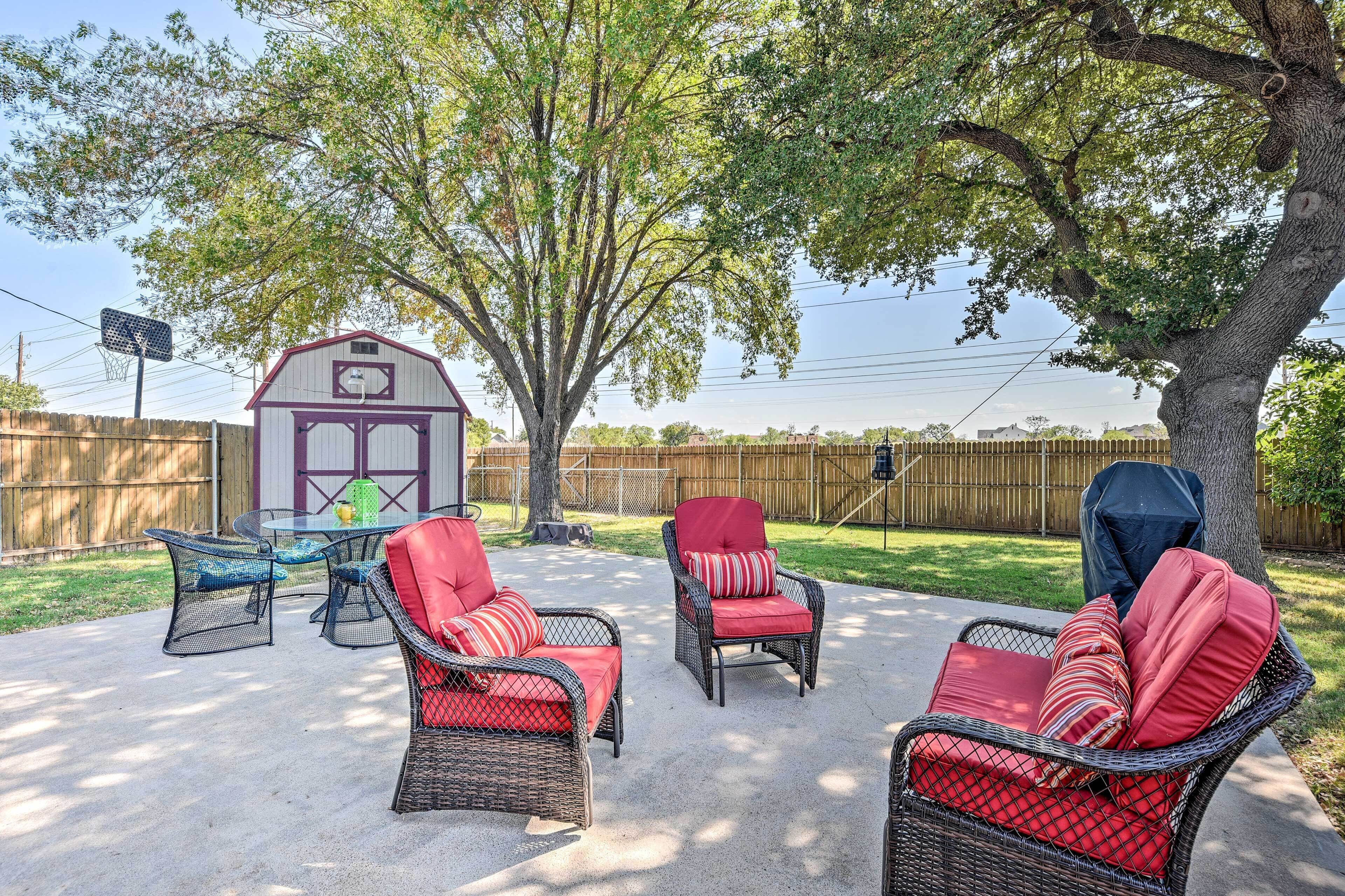 Un patio trasero con muebles de mimbre y un cobertizo pequeño.