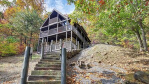 A wooden cabin with a balcony, surrounded by autumn foliage. - Prime Views! Above & Beyond Pigeon Forge Cabin (Sevierville)