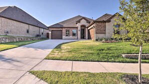 A residential building with a brick facade, a driveway, and a well-maintained lawn. - Aledo Home: Covered Patio & Yard, Near Fort Worth! (Aledo)