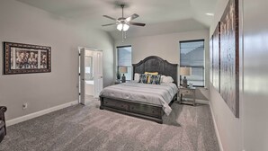 A bedroom with a bed, a ceiling fan, a door, and a window with blinds. - Aledo Home: Covered Patio & Yard, Near Fort Worth! (Aledo)