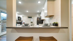 A modern kitchen with a central island, two wooden stools, and built-in appliances. - Alluring Anchorage Apt - Walk to Coastal Trl! (Anchorage)