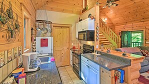 A wooden cabin interior with a kitchen, dining area, and a staircase. - Rustic Andrews Cabin Rental w/ Deck + Fire Pit! (Andrews)