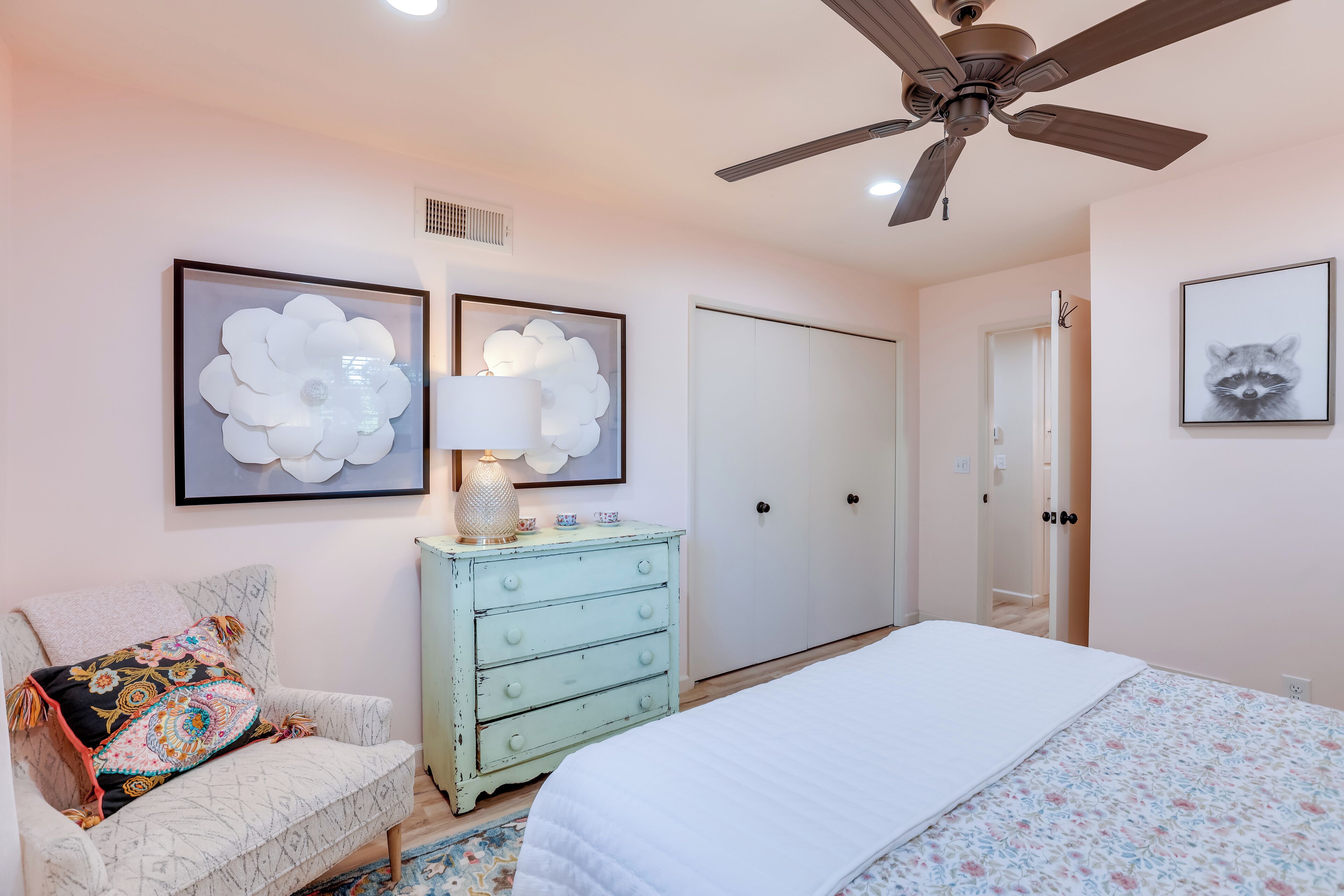 A bedroom with a bed, a dresser, a chair, and two wall art pieces.