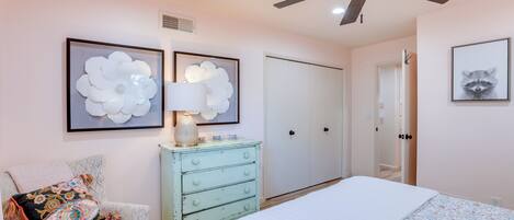 A bedroom with a bed, a dresser, a chair, and two wall art pieces.