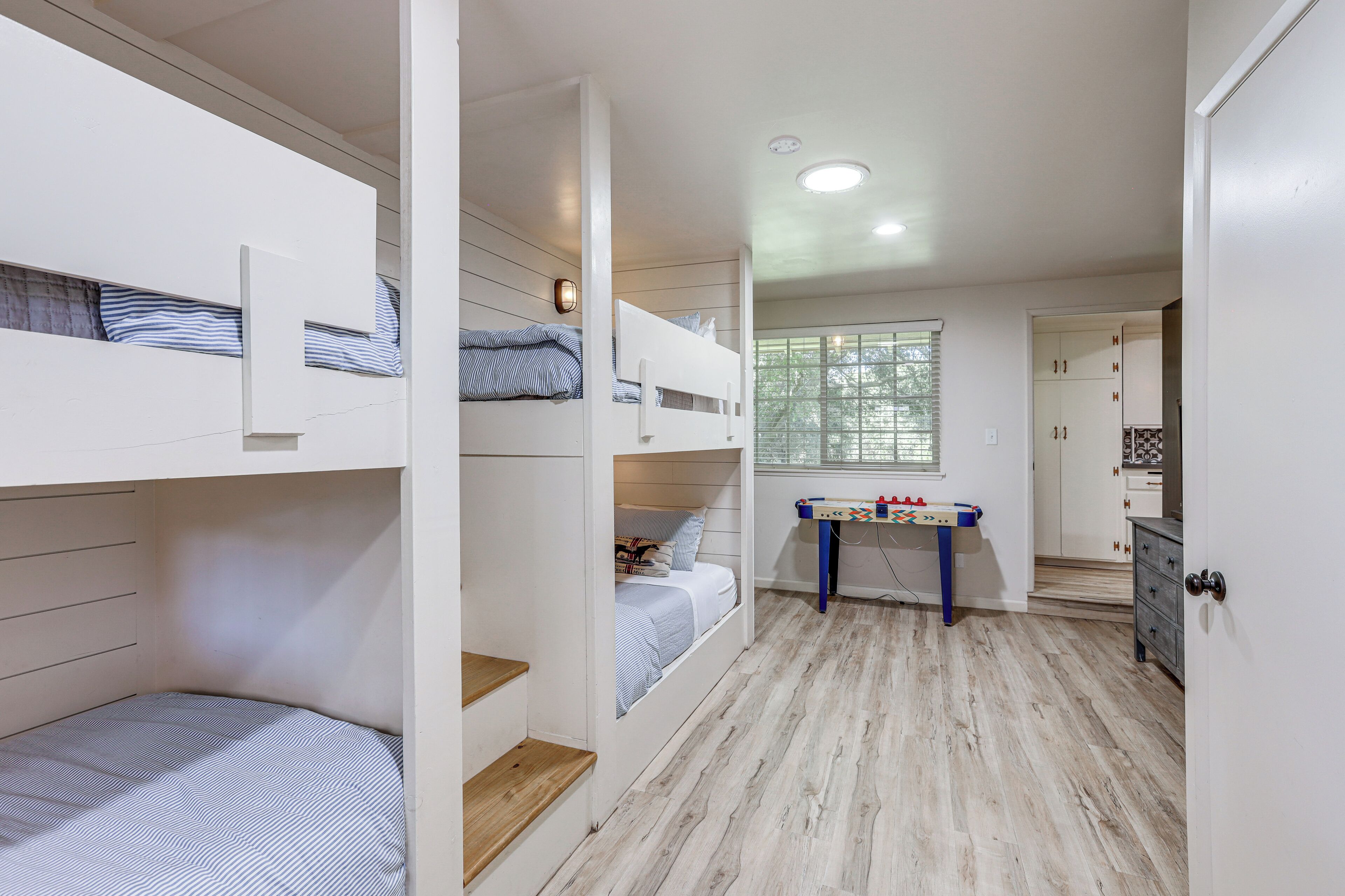 Une chambre d’enfant avec des lits superposés, un petit bureau et une armoire.