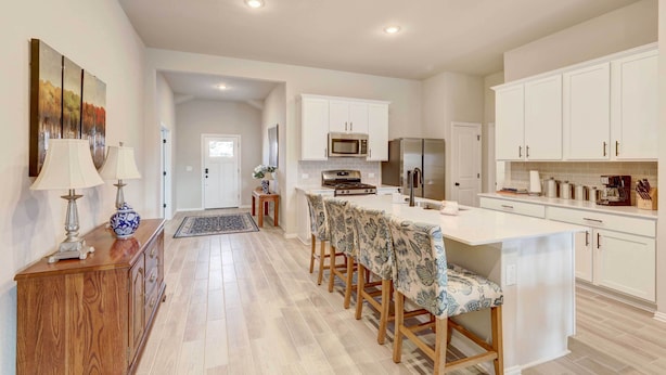 A modern kitchen with white cabinets, a central island with bar stools, a microwave, and a refrigerator. - Bastrop Home w/ Yard, 28 Mi to Austin! (Bastrop)