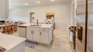 A modern kitchen with white cabinetry, a central island, a dishwasher, a stove, and a refrigerator. - Bastrop Home w/ Yard, 28 Mi to Austin! (Bastrop)