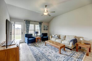 A living room with a ceiling fan, a television, a sofa, a coffee table, and a rug. - Bastrop Home w/ Yard, 28 Mi to Austin! (Bastrop)