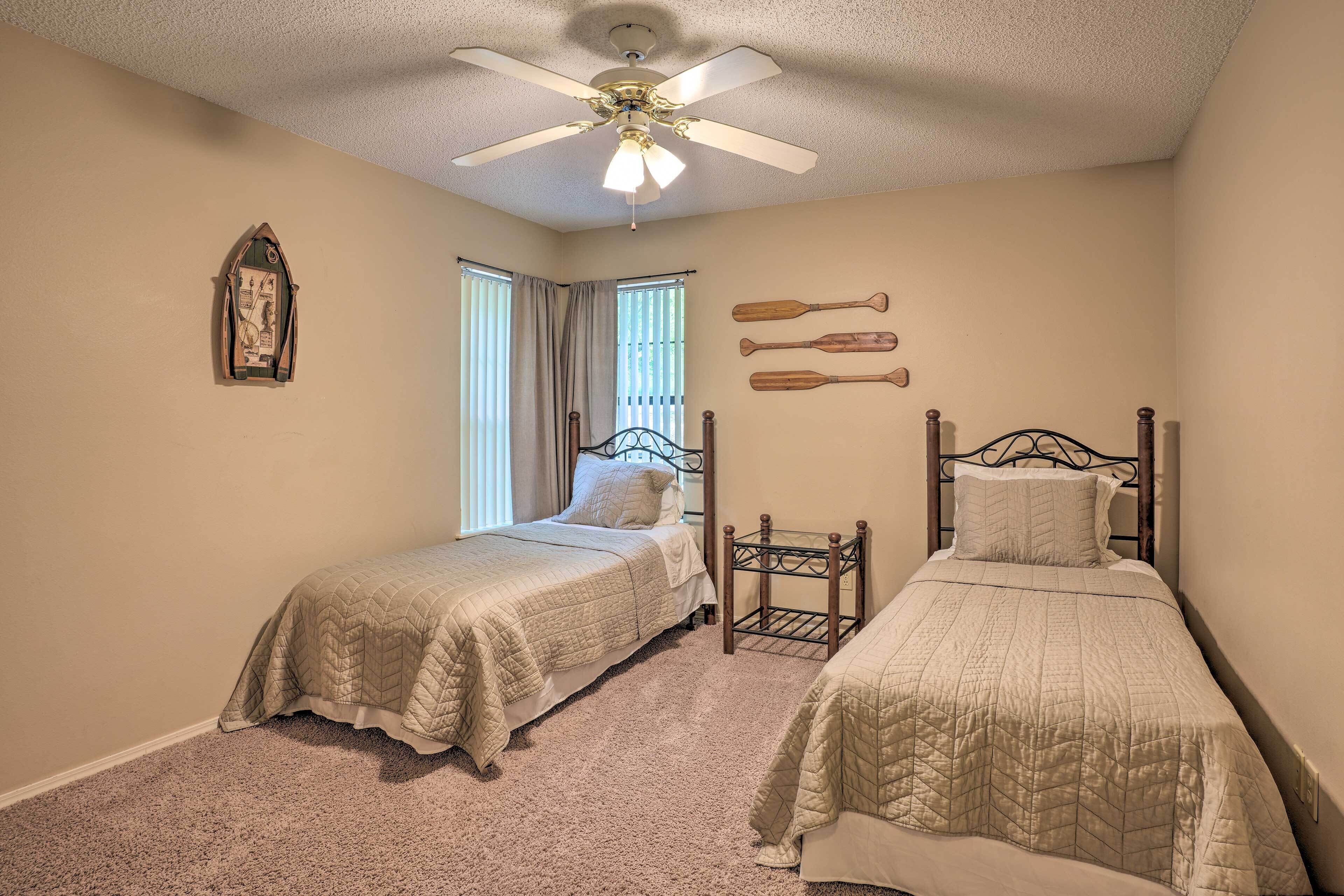 A bedroom with two beds, a ceiling fan, and a window with curtains.