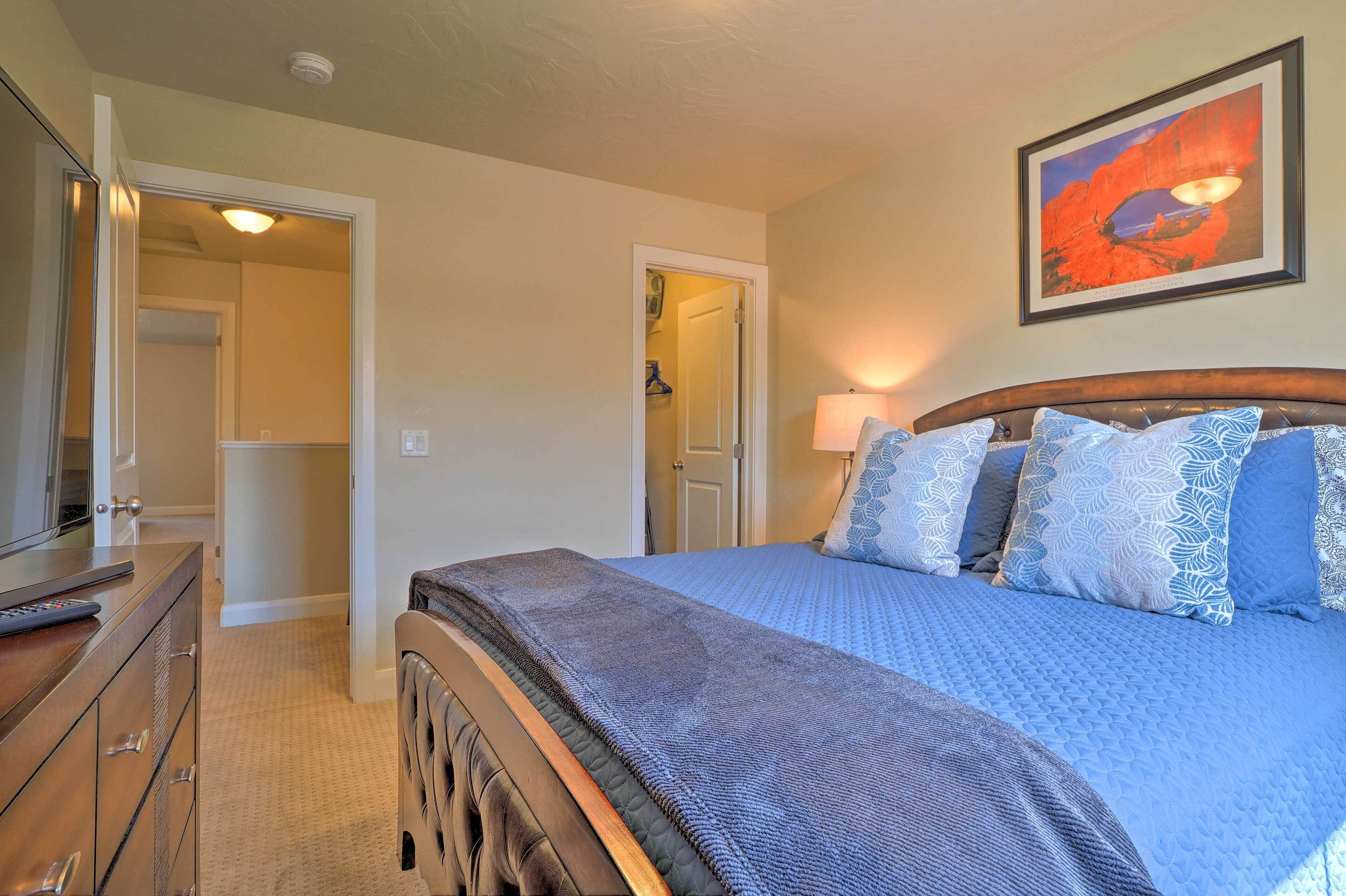 A bedroom with a bed, dresser, and a door leading to another room.