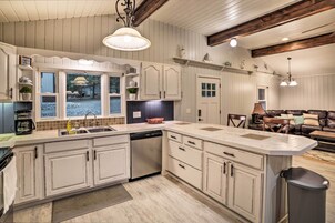 A spacious kitchen with a large island, white cabinetry, and a view to the outside.