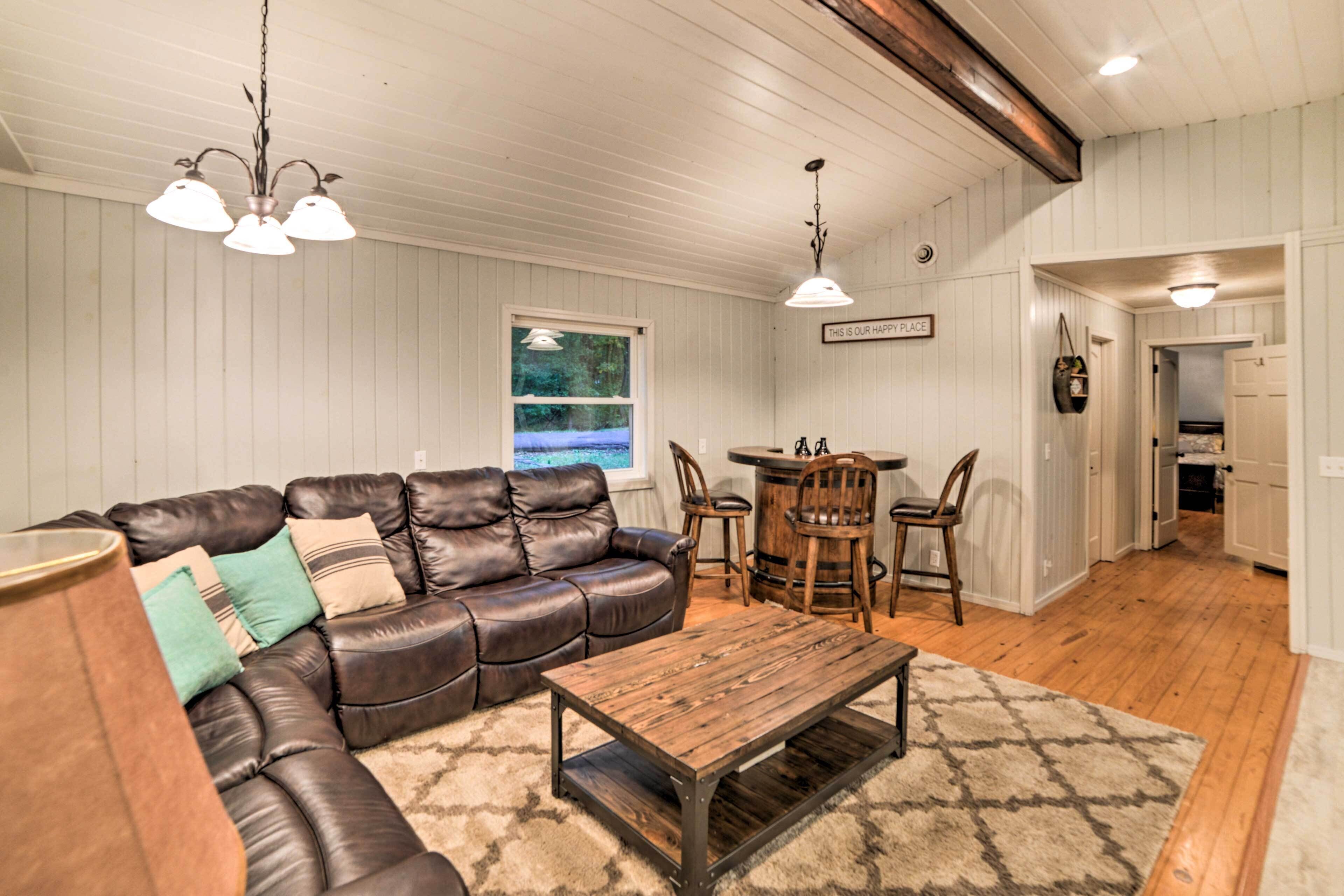 A living room with a leather sofa, wooden coffee table, and a dining area with a table and chairs.