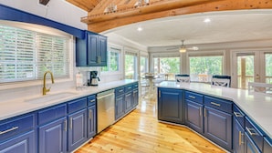 Una cocina amplia con armarios azules, lavavajillas y techo de madera.