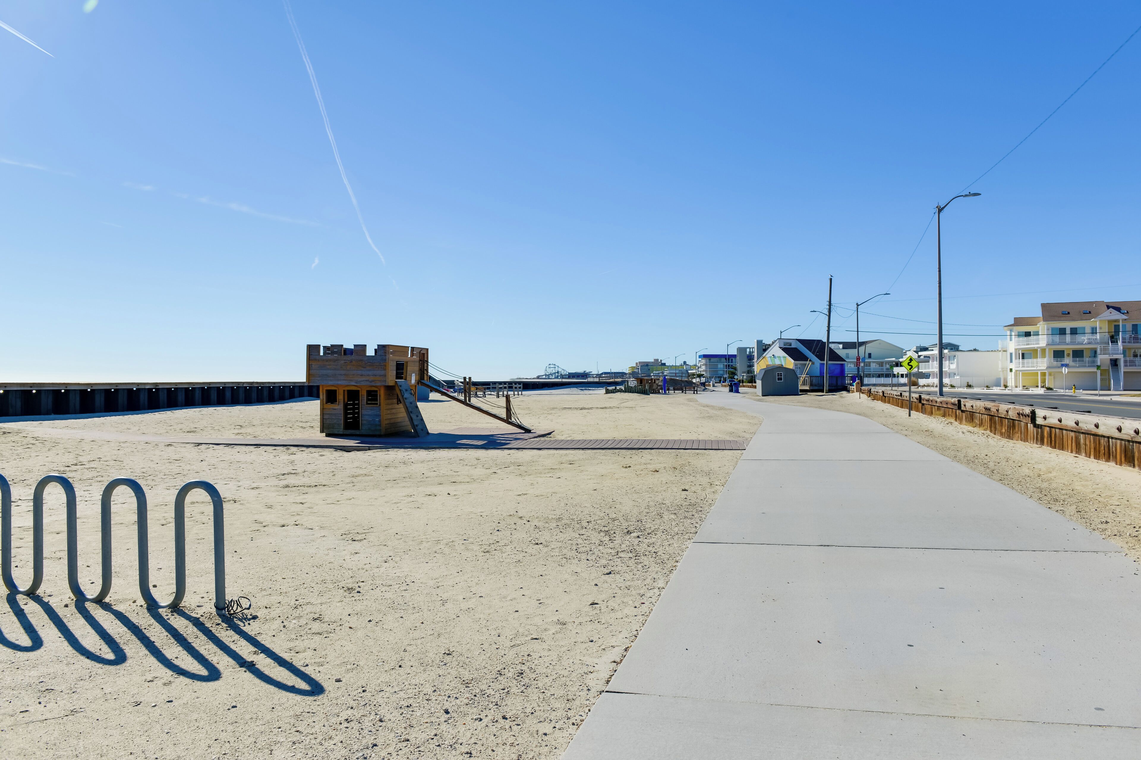 A beachside promenade with a lifeguard tower, a wooden boardwalk, and a sandy beach.