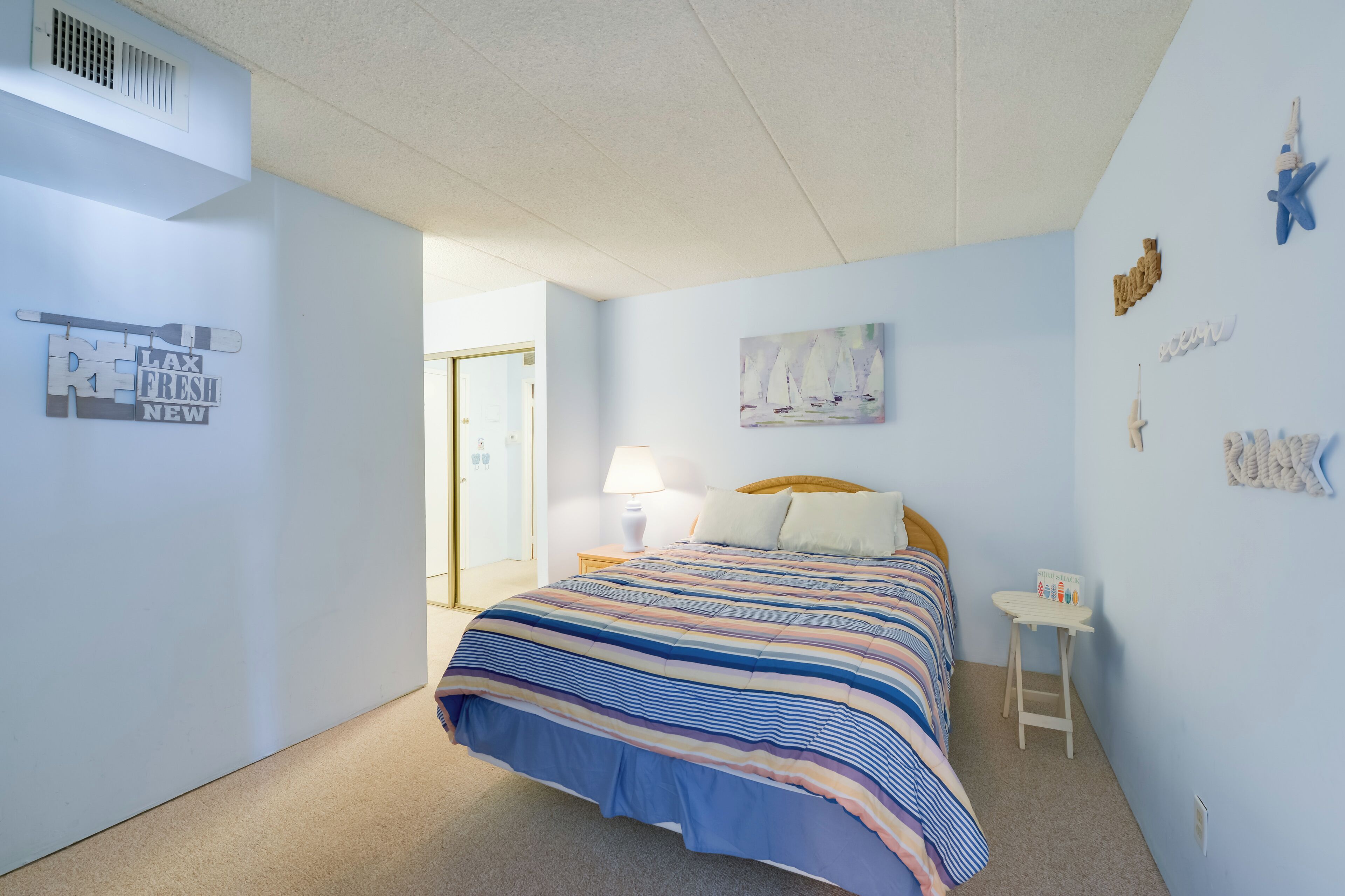 Une chambre à coucher avec un lit, une table de chevet, une lampe et une petite table.