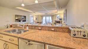 A modern kitchen with granite countertops, stainless steel appliances, and pendant lighting. - Beachfront Traverse City Resort Condo w/ Pool (Traverse City)