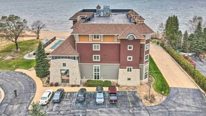A multi-story building with a parking lot and a view of a lake. - Beachfront Traverse City Resort Condo w/ Pool (Traverse City)