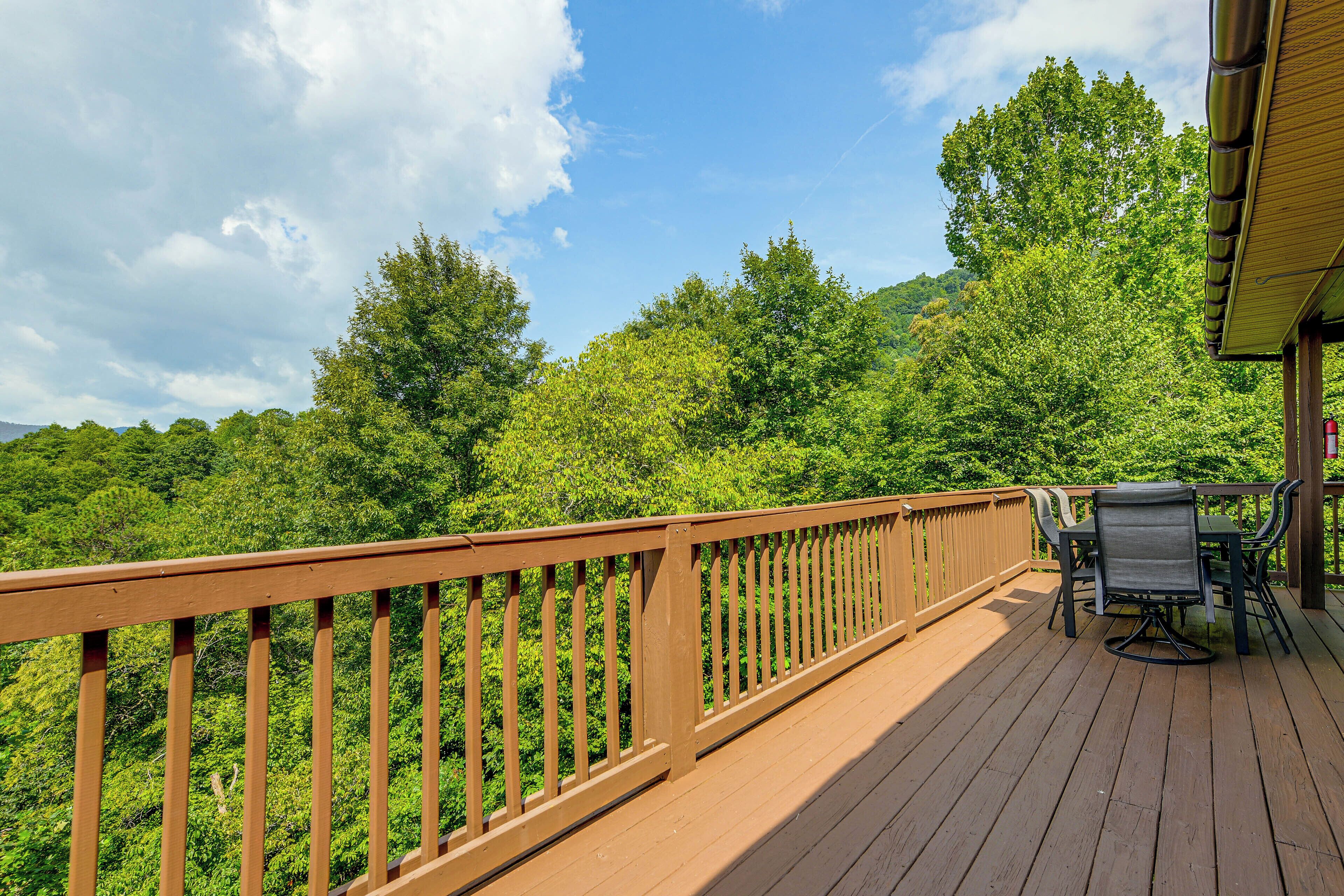 A wooden deck with a railing, a table with chairs, and a fire extinguisher.