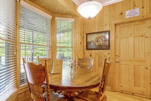 A wooden dining room with a round table, chairs, and a framed picture on the wall.