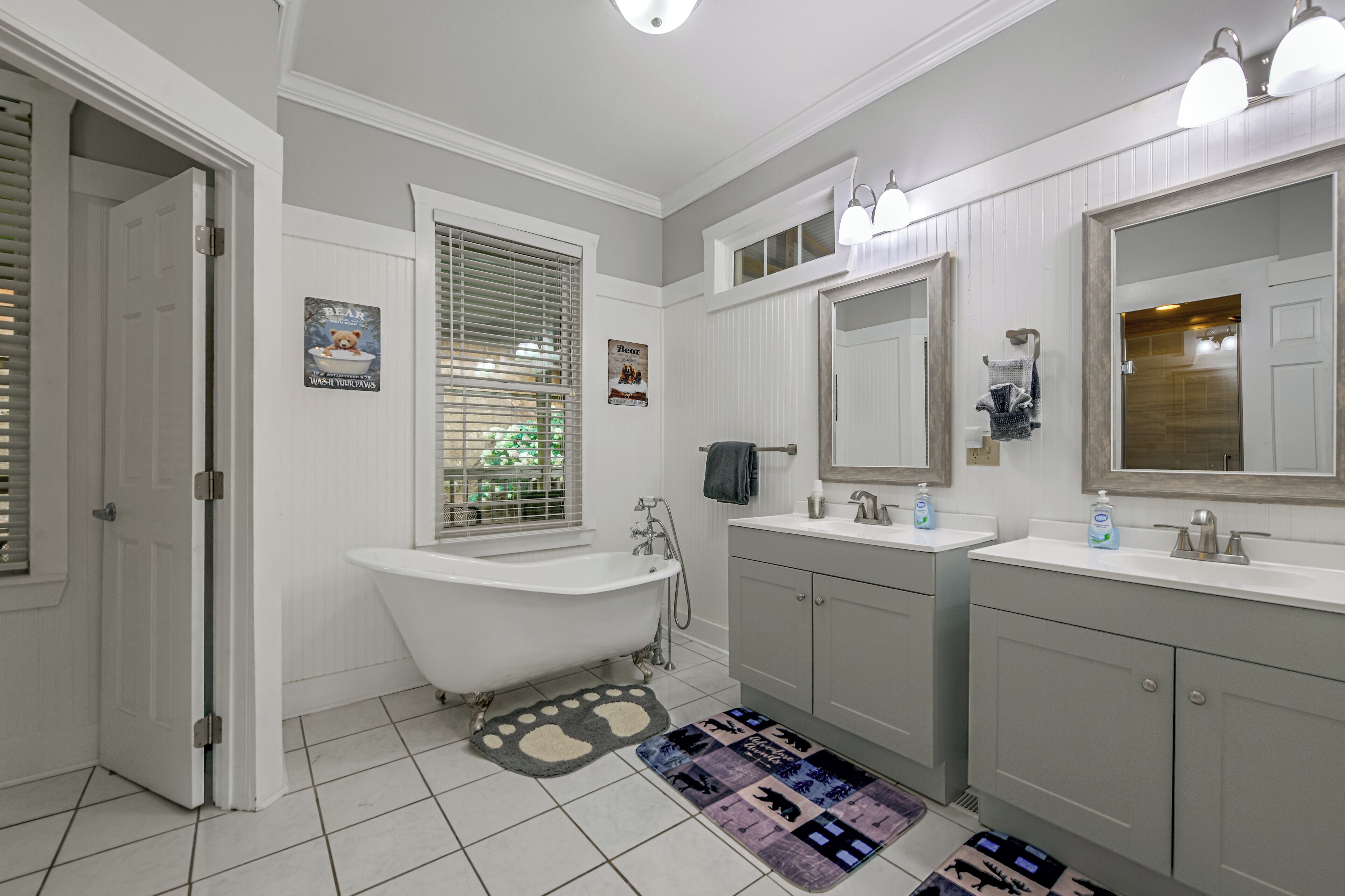 A bathroom with a clawfoot bathtub, a double sink vanity, and a large mirror above the vanity.