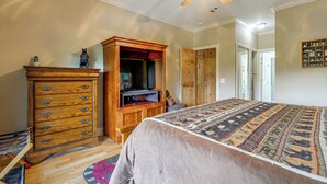 Un dormitorio con una cama grande, un armario de madera, un ventilador de techo y un televisor.