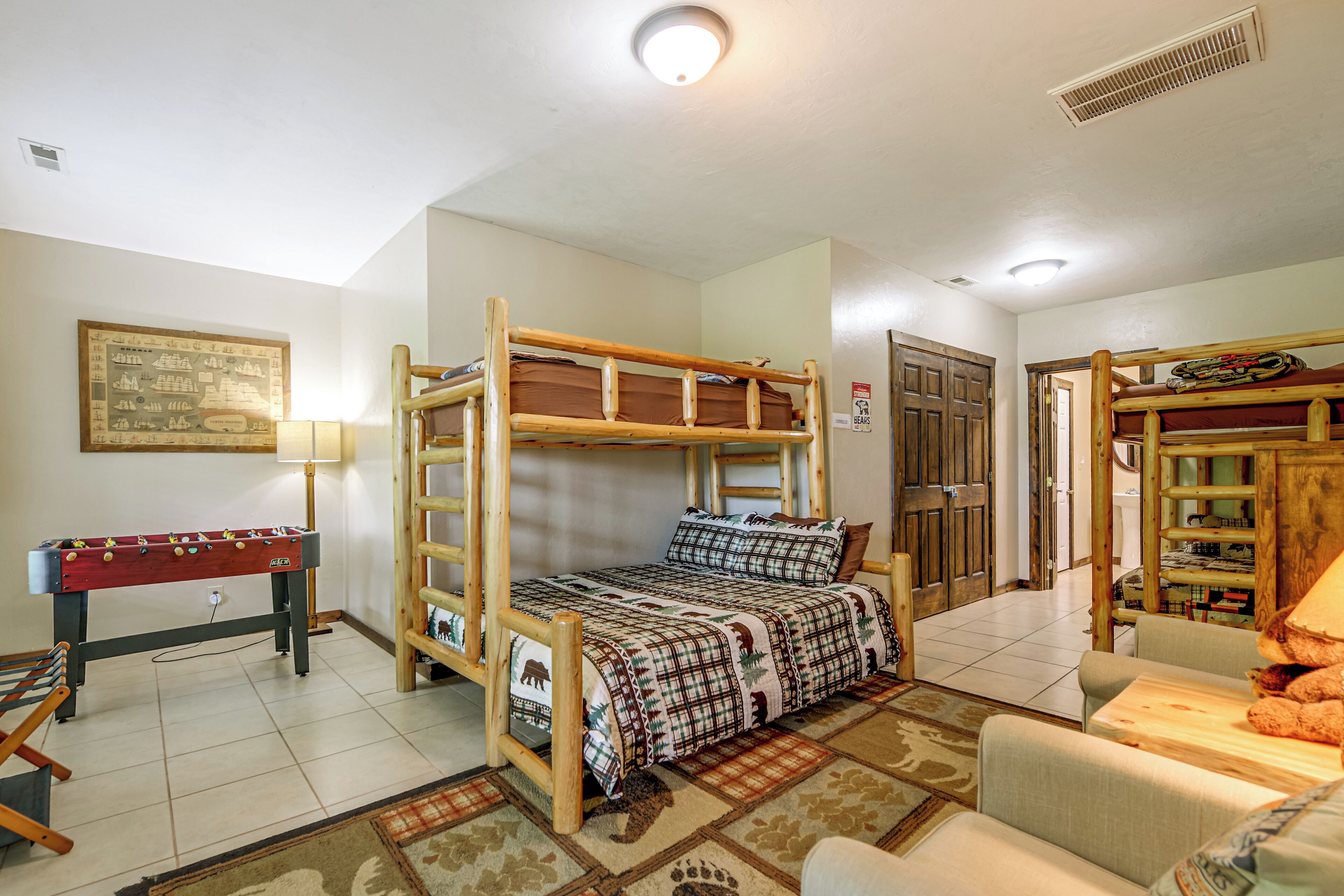 A bunk bed with a wooden frame, a foosball table, a lamp, and a patterned rug.