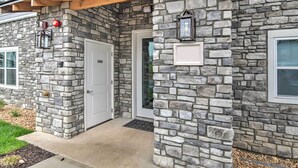 A stone exterior with a white door, a small window, and a stone pillar with a light fixture. - 4BR Sleeps 10 Game Room 4 Mi to SDC (Branson)