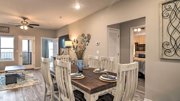 A dining area with a wooden table and white chairs, a vase with dried plants, and a ceiling fan. - 4BR Sleeps 10 Game Room 4 Mi to SDC (Branson)