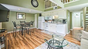 A spacious living area with a dining table and chairs, a kitchen with white cabinets, and a staircase leading to an upper level. - Branson Escape: 9 Mi to Silver Dollar City! (Branson)