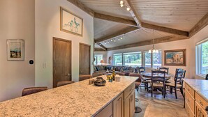 A spacious kitchen with a large island, wooden ceiling beams, and a dining area with a table and chairs. - Angel Fire Home w/ Deck ~ 3 Mi to Ski Resort! (Angel Fire)