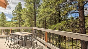 A wooden deck with a table and chairs, surrounded by trees. - Angel Fire Home w/ Deck ~ 3 Mi to Ski Resort! (Angel Fire)