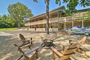 A building with a covered porch and outdoor seating area with Adirondack chairs and a fire pit. - Beautiful Bull Shoals Retreat w/ Lake View! (Bull Shoals)