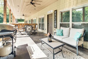 A covered outdoor area with a sofa, chairs, a table, and a gas grill. - Beautiful Bull Shoals Retreat w/ Lake View! (Bull Shoals)