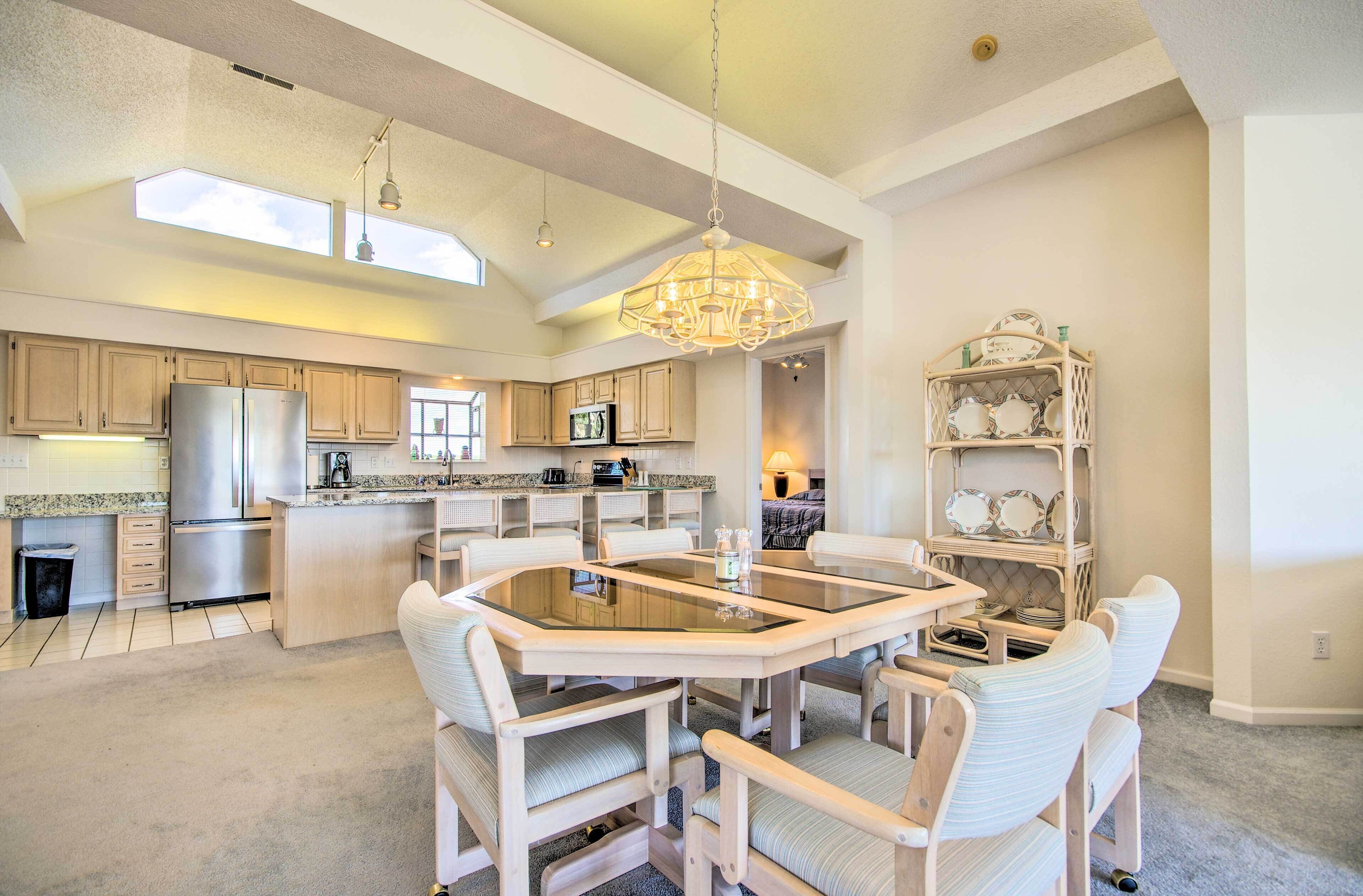 A spacious kitchen with a central island, wooden cabinets, and a chandelier.
