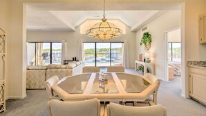 Une salle à manger spacieuse, dotée d’une grande table ovale, d’un lustre et offrant une vue sur l’extérieur grâce à de larges fenêtres.